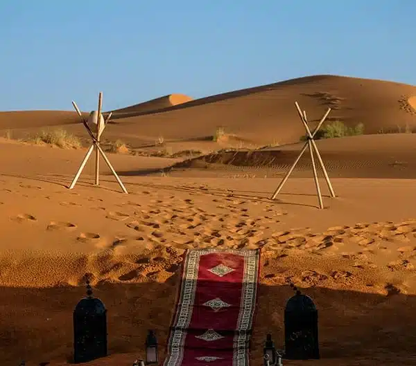 Tapis berbère et lanternes à l'entrée d'un bivouac dans les dunes de Merzouga