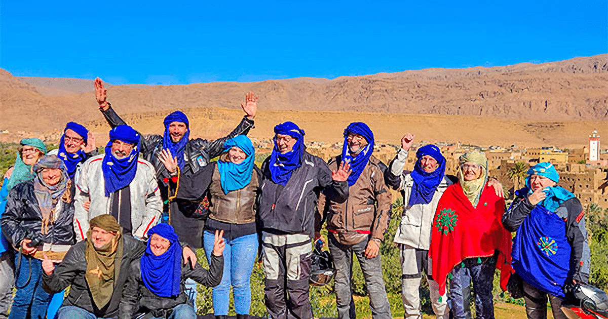 Groupe de motards en tenue berbère célébrant devant un village du sud marocain, circuit ROAD STORY