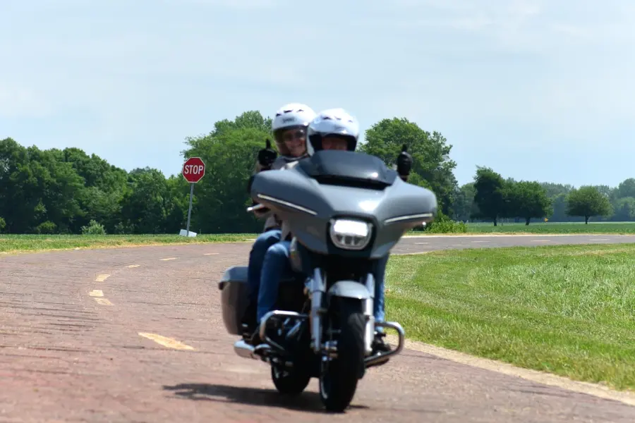 Duo à moto souriant sur une route de campagne, ambiance conviviale d'un voyage moto Route 66