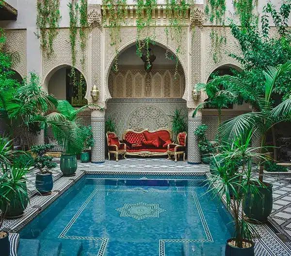 Patio d'un riad marocain avec bassin en zellige et arcs sculptés, hébergement traditionnel au Maroc (Miniature de la destination Maroc)