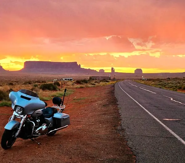 Moto garée face à Monument Valley au coucher de soleil, miniature de notre voyage moto Ouest Américain