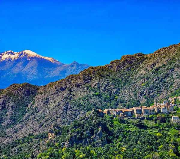 Village de montagne au pied d'un sommet enneigé, Corse