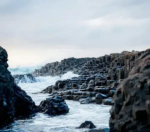 Colonnes de basalte et écume des vagues à la Chaussée des Géants, Irlande du Nord